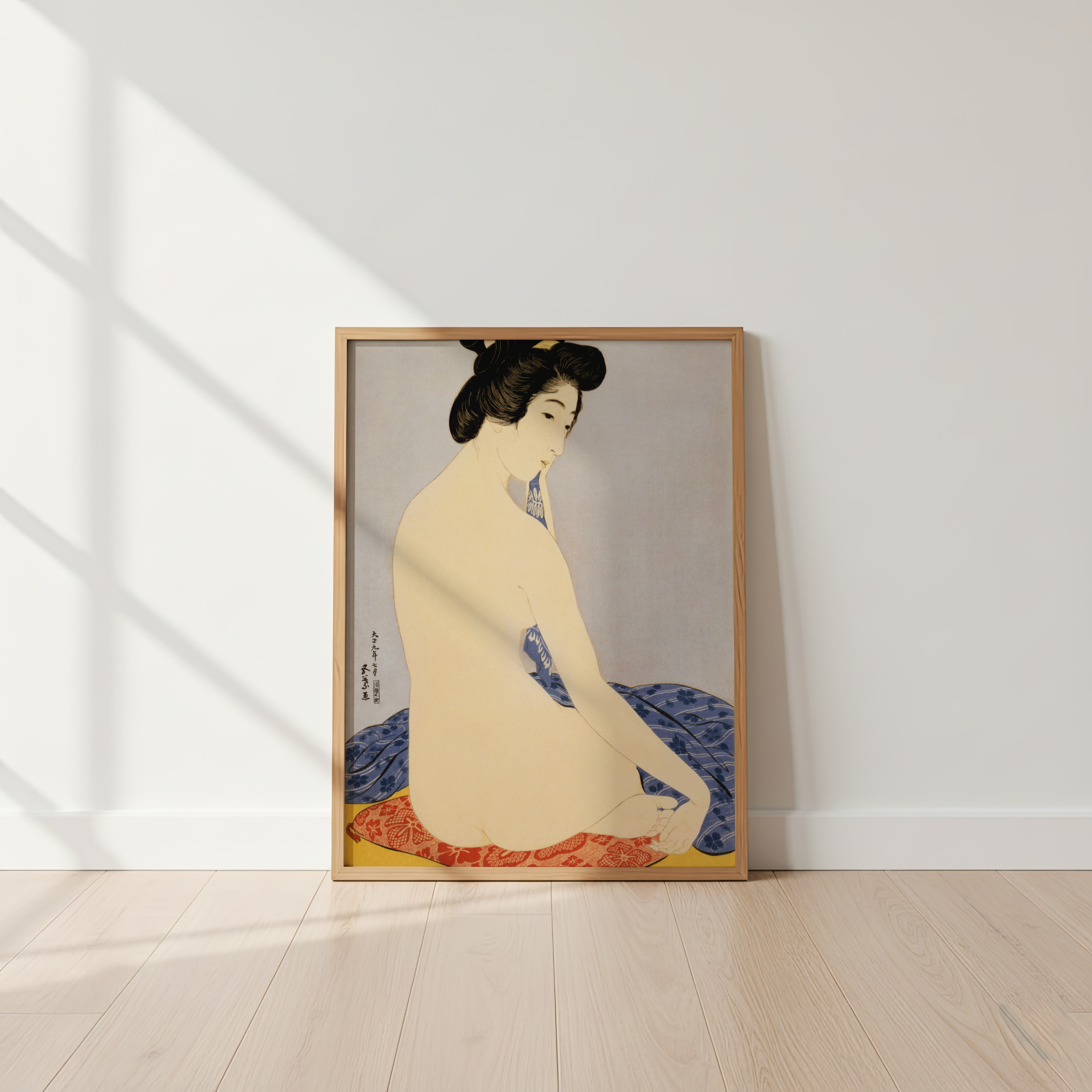 Framed artwork of a seated figure with a blue and red garment on a white wall.