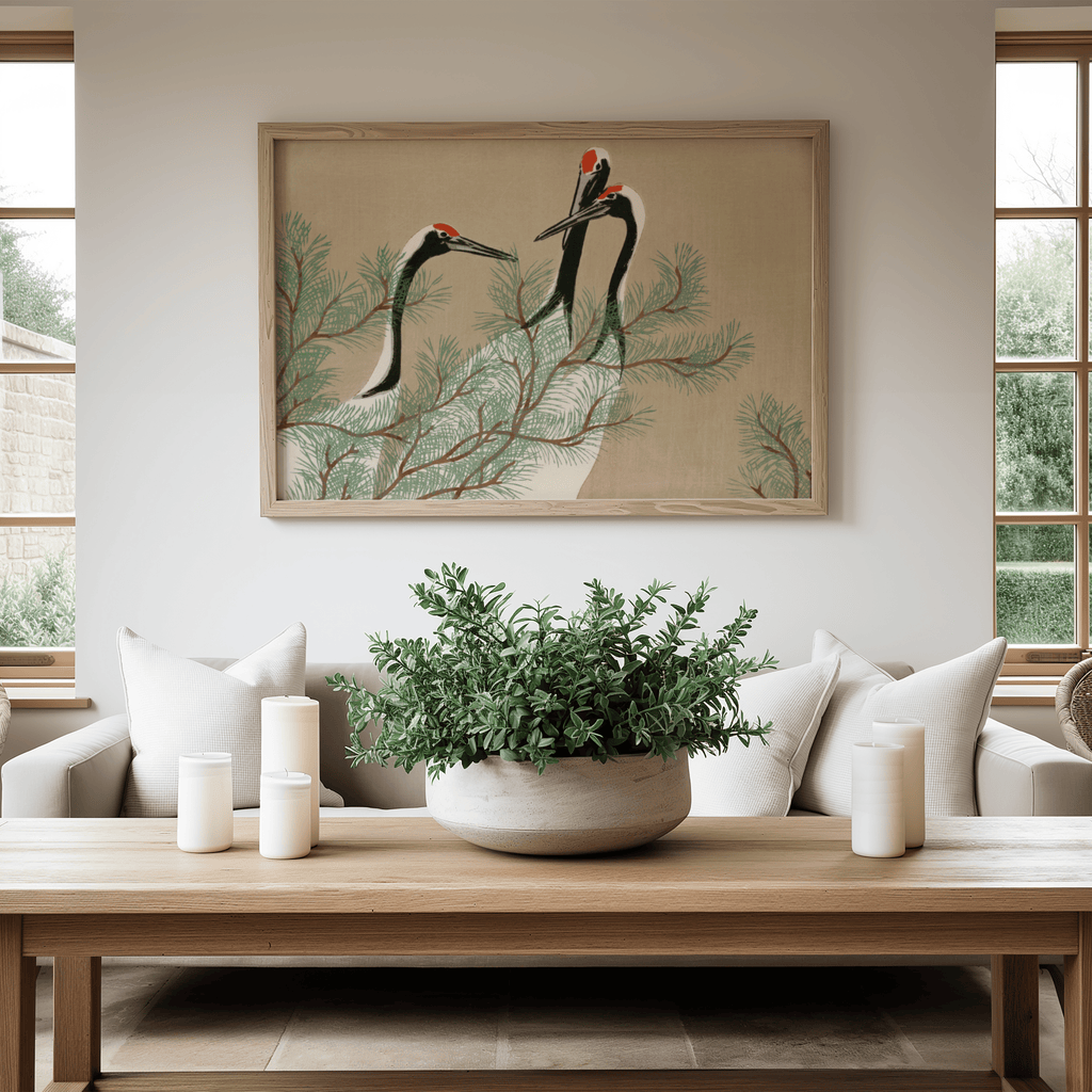 Living room with a framed artwork of cranes on a branch, a potted plant on a coffee table, and a couch.