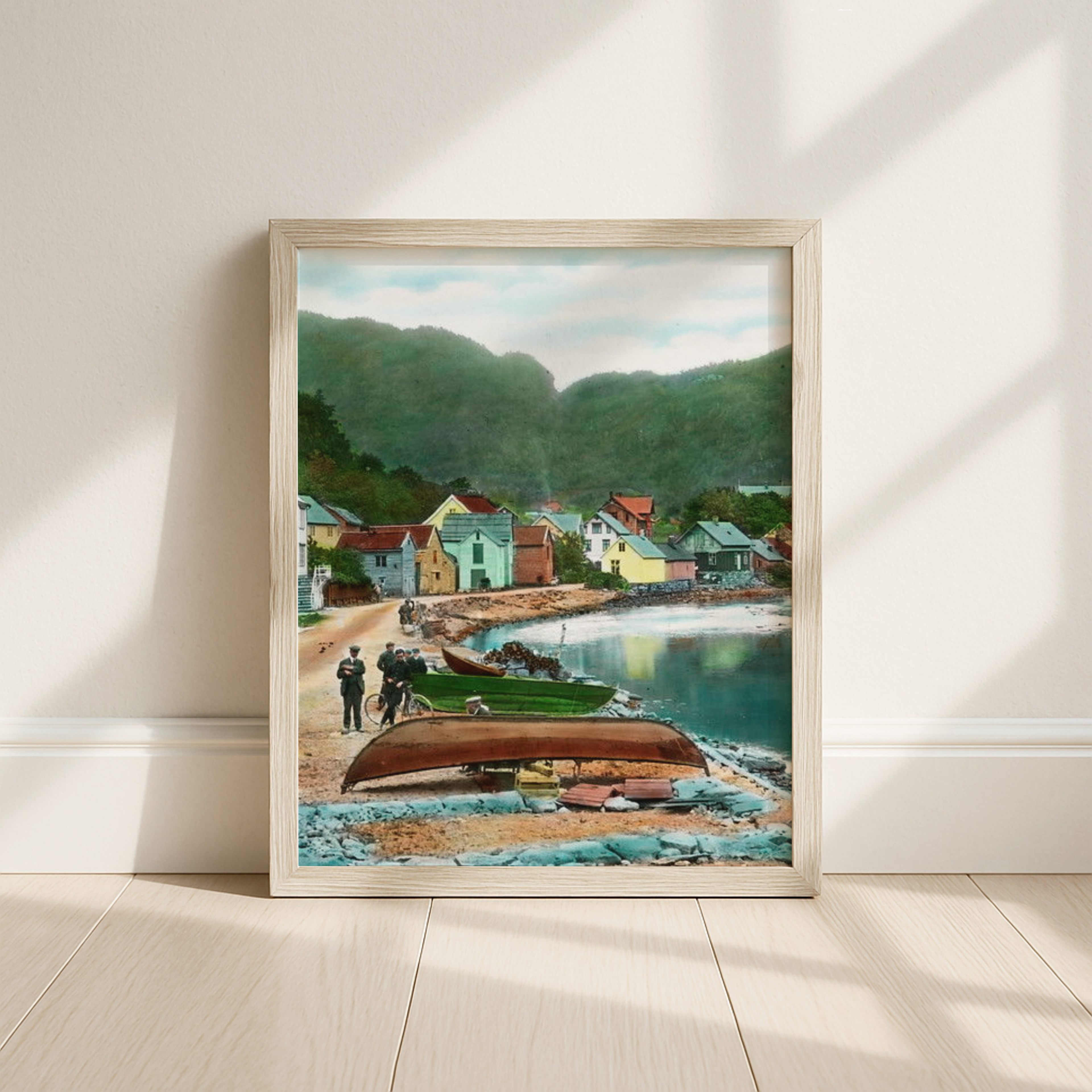 Framed artwork of a coastal scene with houses and boats on a wall.