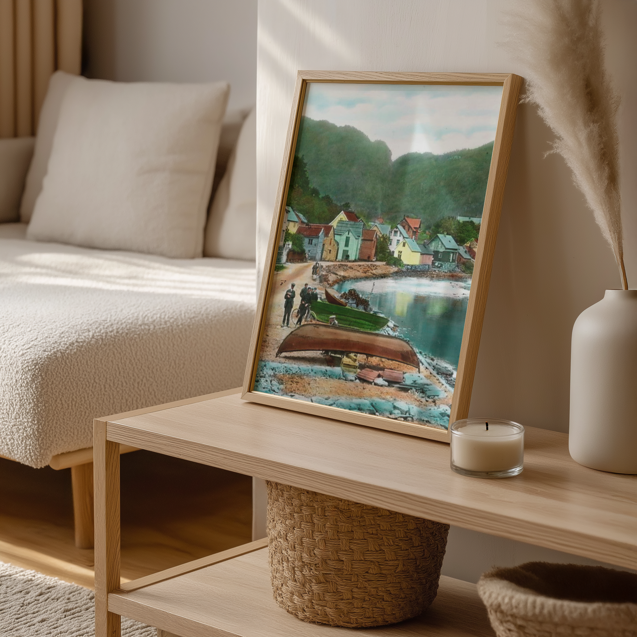Framed artwork of a coastal scene on a wooden coffee table with a candle and decorative items.