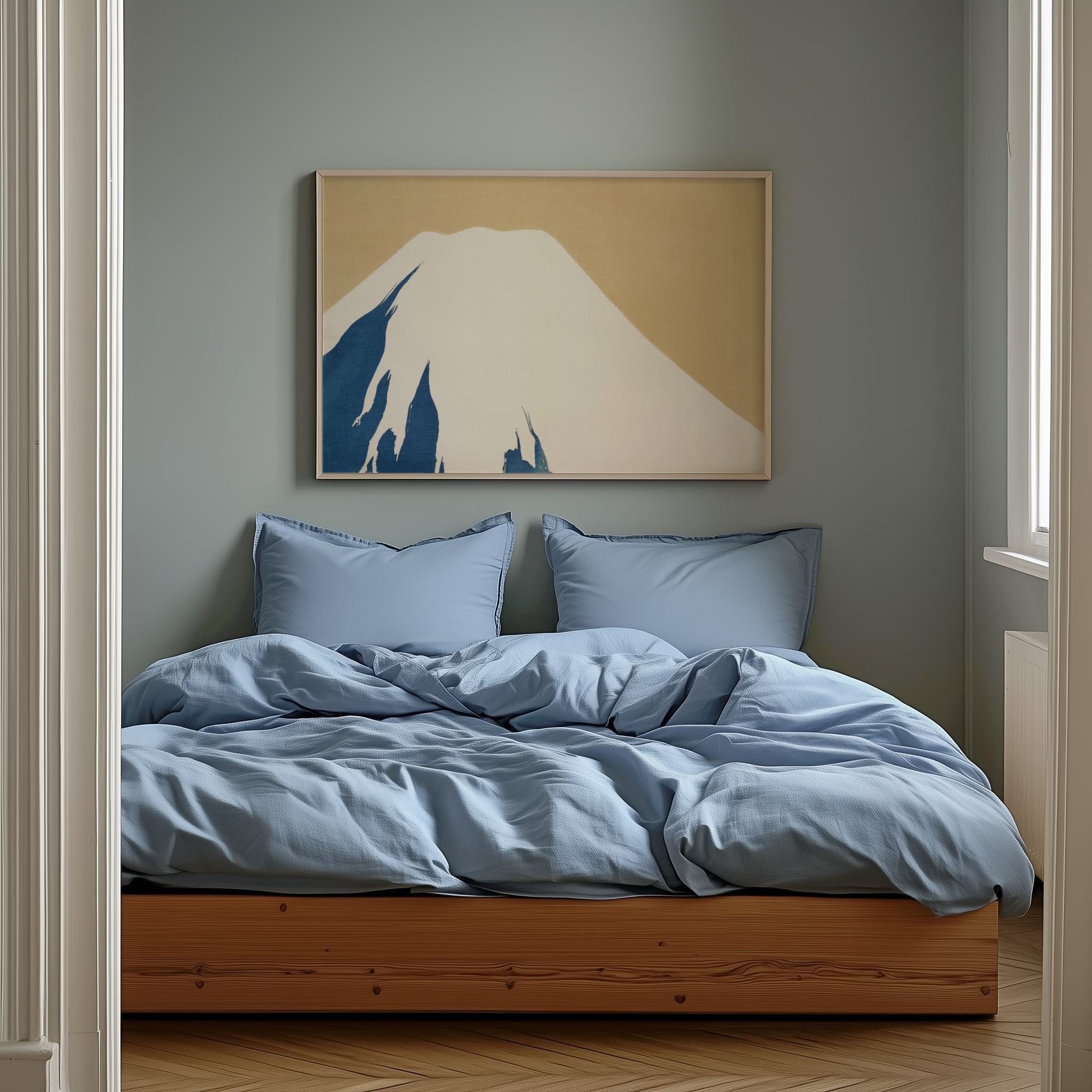 Bedroom with blue bedding and a framed artwork of a mountain on the wall.