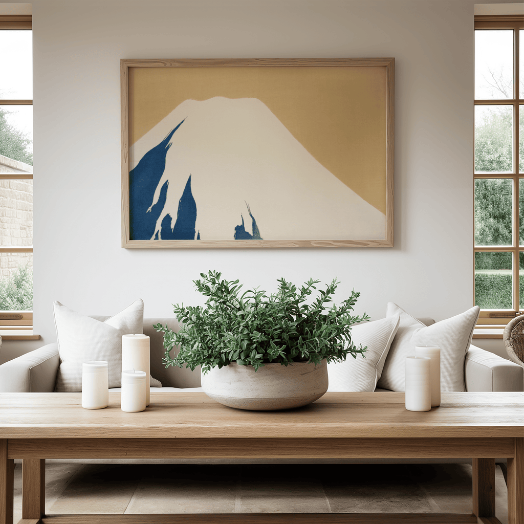 Living room with a framed artwork of a mountain, a potted plant on a coffee table, and white candles.