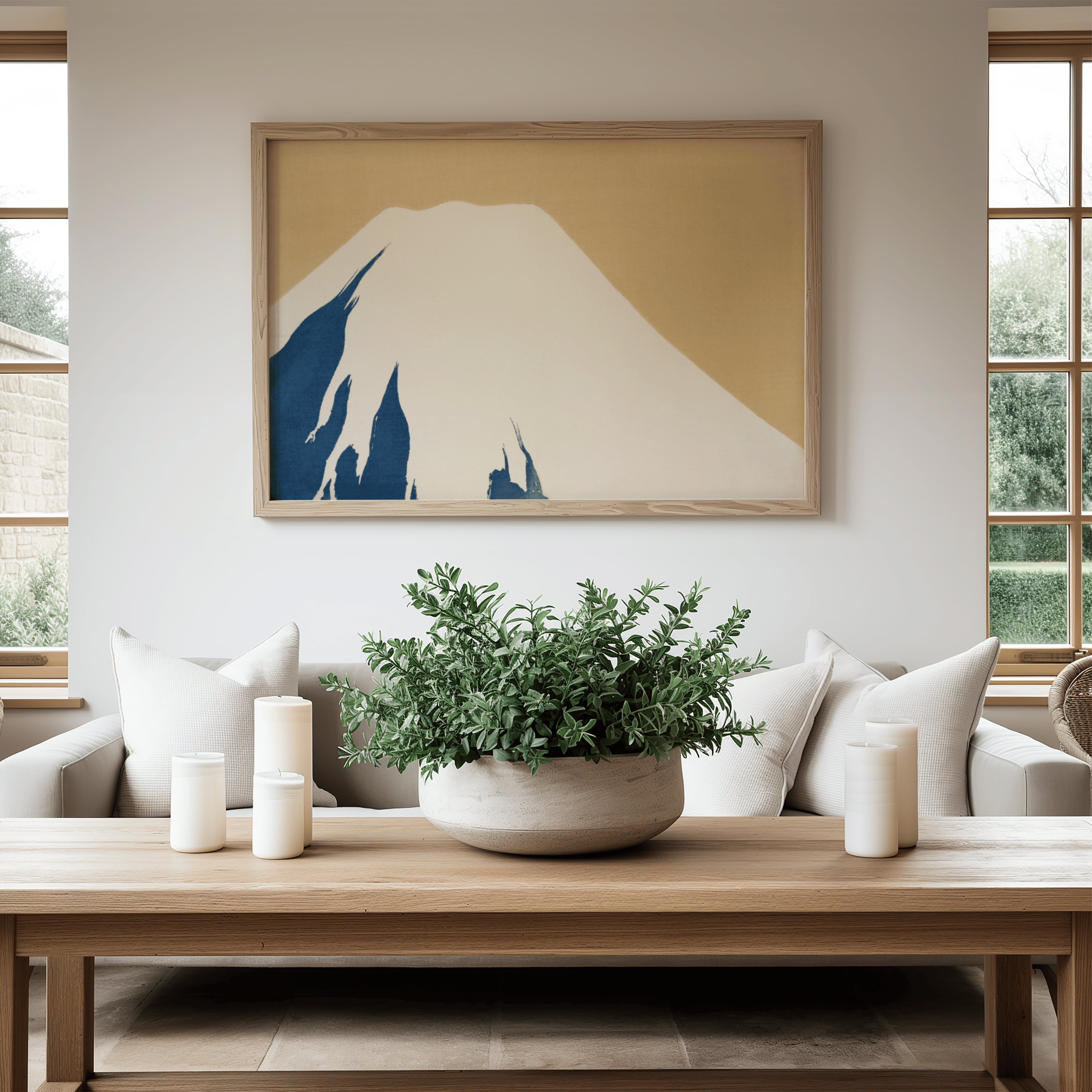 Living room with a framed artwork of a mountain, a potted plant on a coffee table, and white candles.