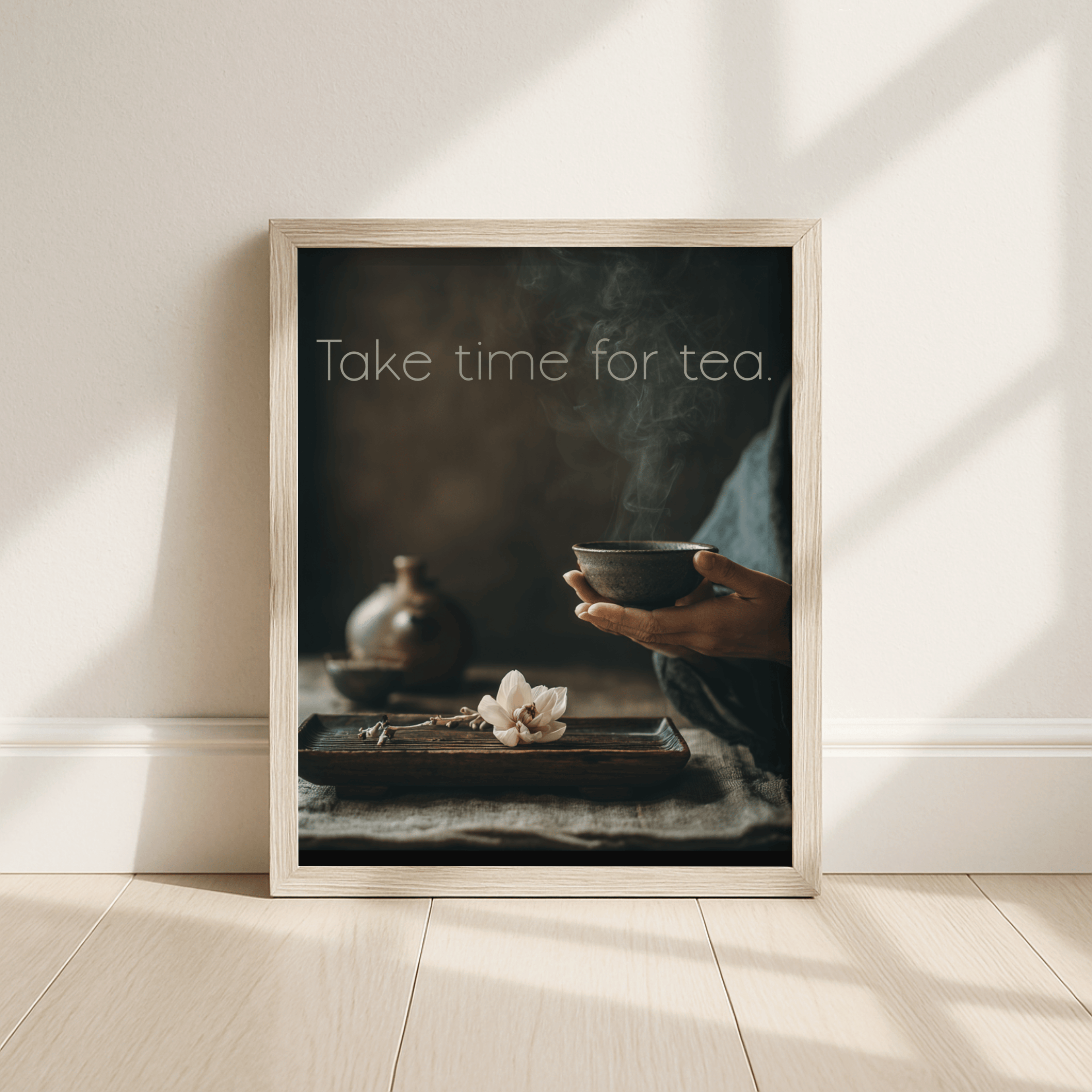 Framed artwork with a person holding a tea bowl and text 'Take time for tea' on a neutral background.