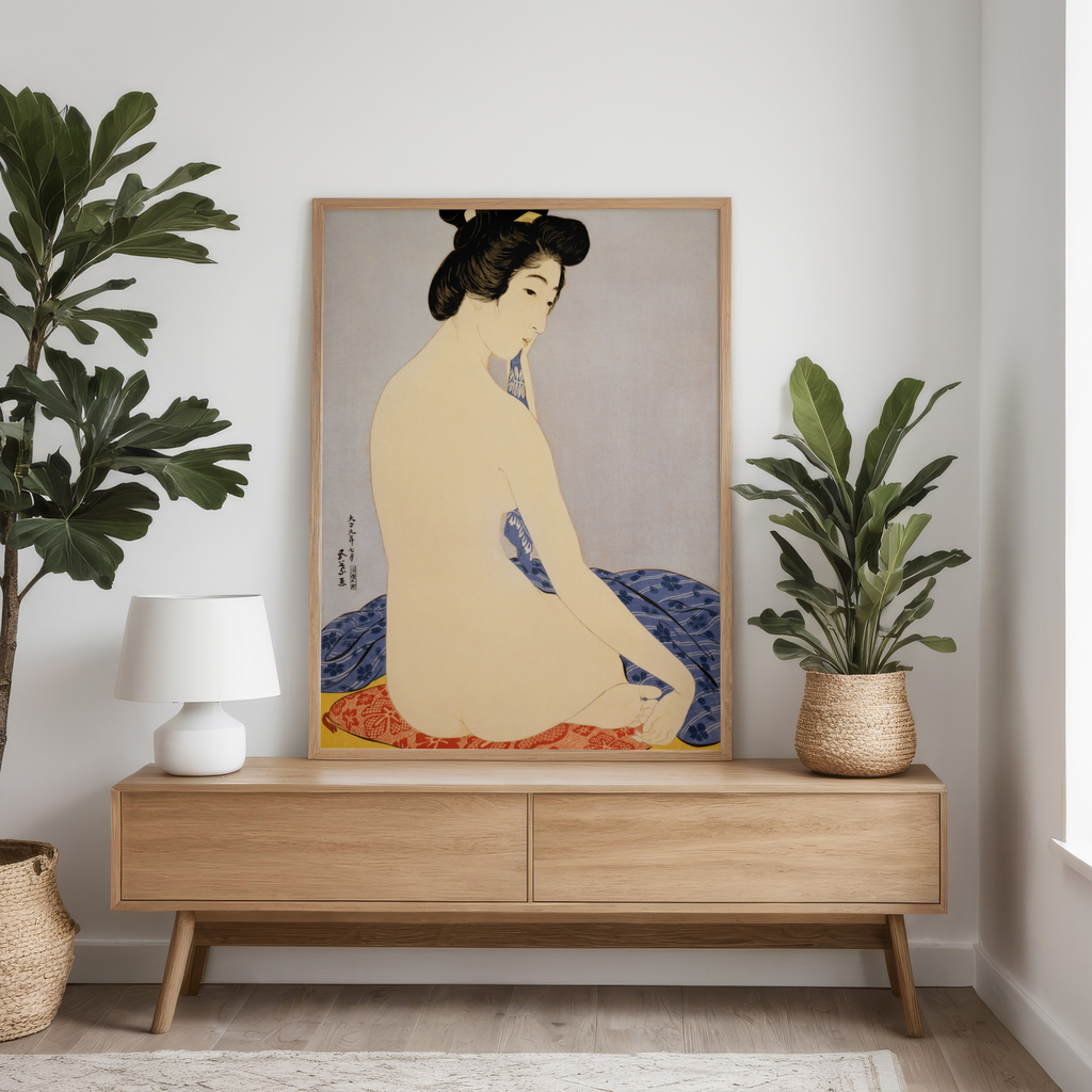 Framed artwork of a traditional Japanese scene on a wooden console table with plants and a lamp.